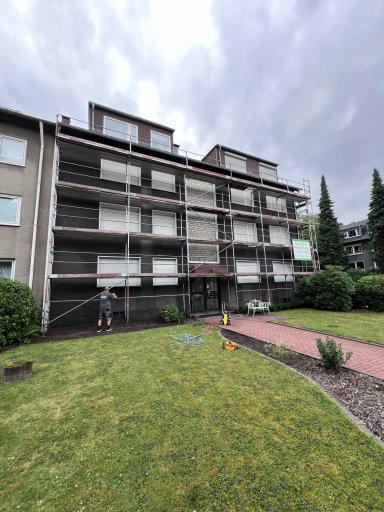 Mehrstöckiges Wohngebäude mit Balkonen und gepflegtem Grünbereich.