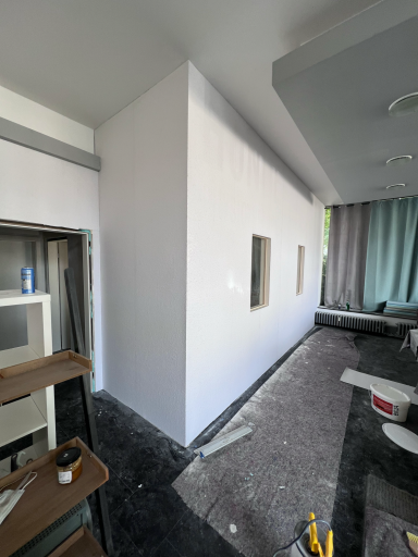 Unvollendete Innenwand mit zwei Fensteröffnungen in einem modern eingerichteten Raum.