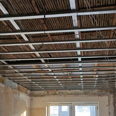 Rohbau mit freiliegender Deckenstruktur und Fenster, unvollständig renoviert.