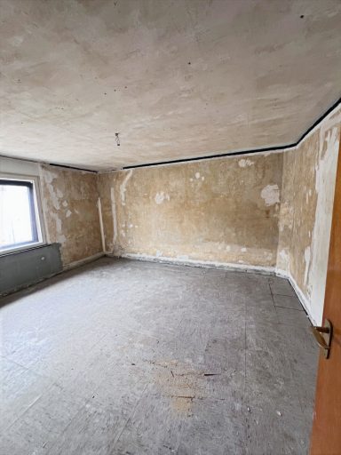 Leere, unrenovierte Zimmer mit älteren Wänden und ohne Möbel.
