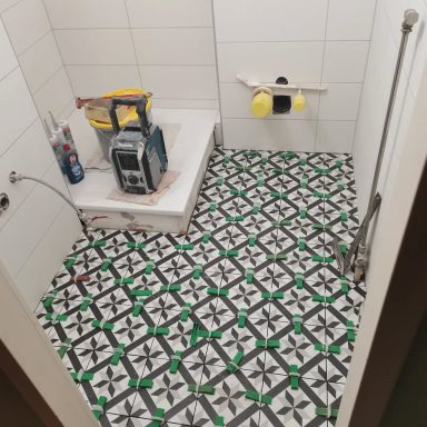 Badezimmer mit Fliesen, Baugeräten und einer Fläche für die Dusche oder Badewanne.